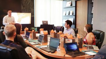 man standing in front of people sitting beside table with laptop computers